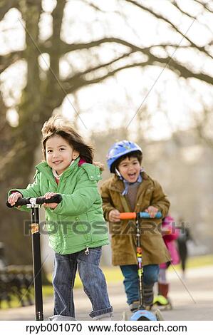 Stock Image - Kids playing with kickboards in a park. Fotosearch