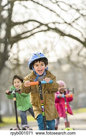 Kids playing with kickboards in a park View Large Photo Image Stock Image - Kids playing with kickboards in a park. Fotosearch