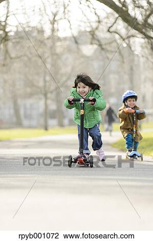 Stock Image - Kids playing with kickboards in a park. Fotosearch