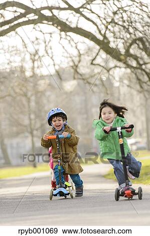 Stock Photo - Kids playing with kickboards in a park. Fotosearch