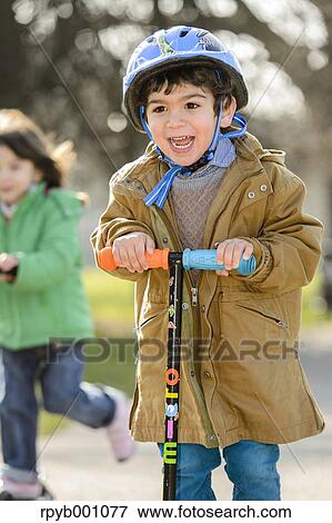 Kids playing with kickboards in a park View Large Photo Image Stock Photo - Kids playing with kickboards in a park. Fotosearch