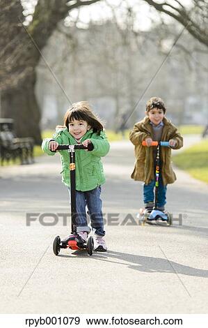 Kids playing with kickboards in a park View Large Photo Image Stock Photo - Kids playing with kickboards in a park. Fotosearch
