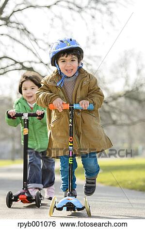 Kids playing with kickboards in a park View Large Photo Image Stock Photograph - Kids playing with kickboards in a park. Fotosearch