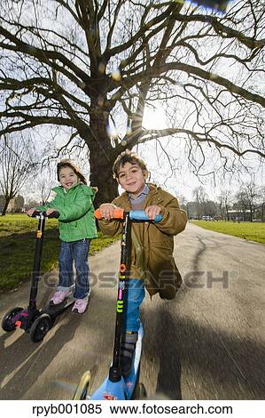 Stock Photography - Kids playing with kickboards in a park. Fotosearch