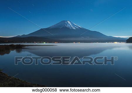 Stock Photo - Night view of cloudy sky and Mount Fuji at night from Lake Yamanaka, Yamanashi Prefecture, Japan. Fotosearch