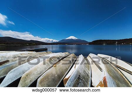 Stock Photo - Night view of cloudy sky Mount Fuji and boats at Lake Yamanaka, Yamanashi Prefecture, Japan. Fotosearch
