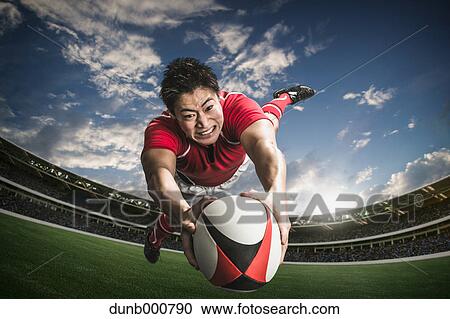 Stock Image - Portrait of Japanese rugby player diving to score a try. Fotosearch