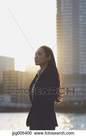 Stock Image - Portrait of young Japanese businesswoman by a river downtown Tokyo. Fotosearch