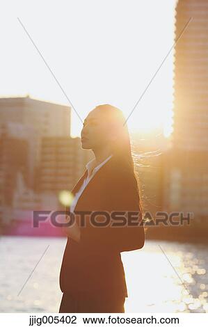 Stock Image - Portrait of young Japanese businesswoman by a river downtown Tokyo. Fotosearch