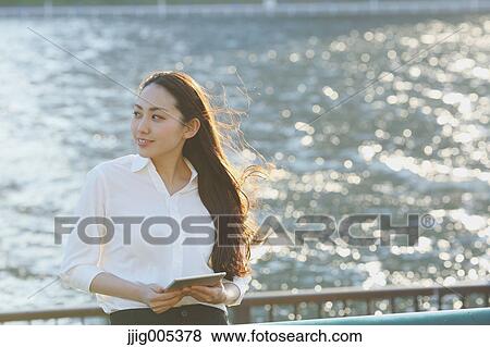 Portrait of young Japanese businesswoman by a river downtown Tokyo View Large Photo Image Stock Photo - Portrait of young Japanese businesswoman by a river downtown Tokyo. Fotosearch
