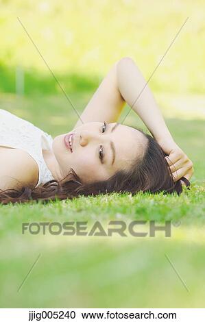 Portrait of young Japanese woman laying on green grass View Large Photo Image Stock Image - Portrait of young Japanese woman laying on green grass. Fotosearch