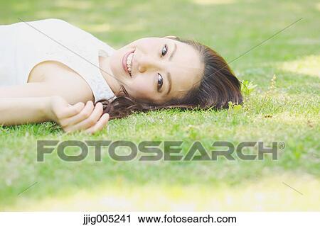 Portrait of young Japanese woman laying on green grass View Large Photo Image Stock Image - Portrait of young Japanese woman laying on green grass. Fotosearch