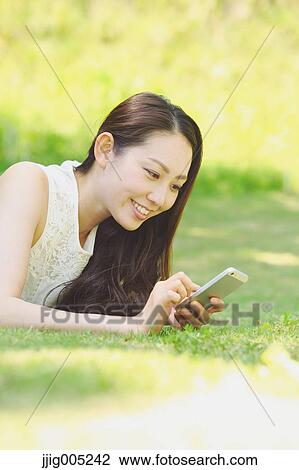 Portrait of young Japanese woman laying on grass with smartphone View Large Photo Image Stock Image - Portrait of young Japanese woman laying on grass with smartphone. Fotosearch