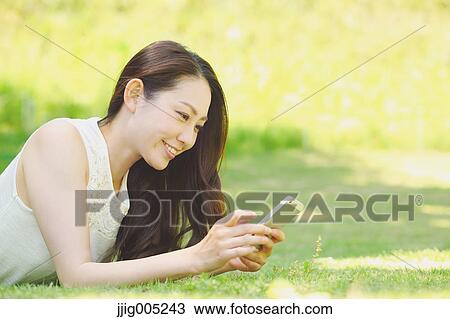 Portrait of young Japanese woman laying on grass with smartphone View Large Photo Image Stock Image - Portrait of young Japanese woman laying on grass with smartphone. Fotosearch
