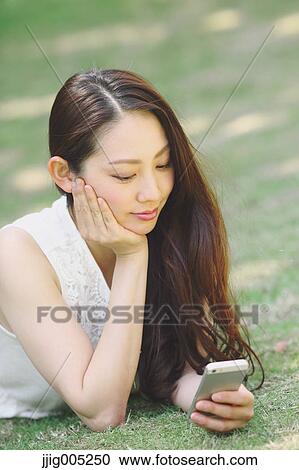 Portrait of young Japanese woman laying on grass with smartphone View Large Photo Image Stock Image - Portrait of young Japanese woman laying on grass with smartphone. Fotosearch
