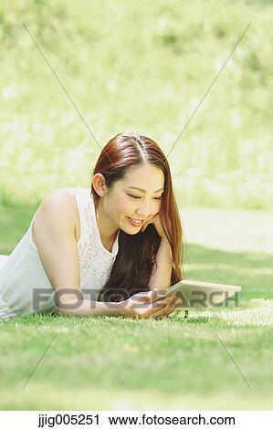 Portrait of young Japanese woman laying on grass with tablet View Large Photo Image Stock Image - Portrait of young Japanese woman laying on grass with tablet. Fotosearch