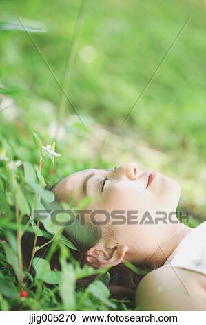 Portrait of young Japanese woman laying on green grass View Large Photo Image Stock Image - Portrait of young Japanese woman laying on green grass. Fotosearch