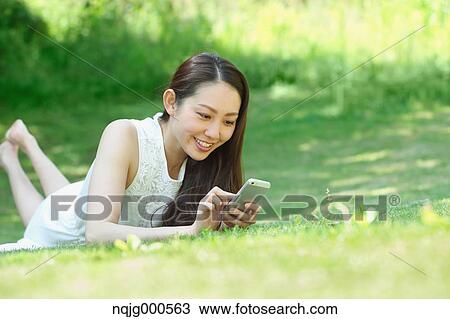 Portrait of young Japanese woman laying on grass with smartphone View Large Photo Image Stock Image - Portrait of young Japanese woman laying on grass with smartphone. Fotosearch