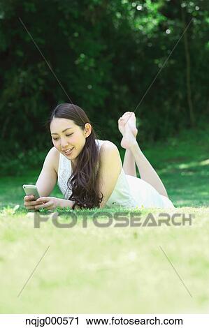 Portrait of young Japanese woman laying on grass with smartphone View Large Photo Image Stock Image - Portrait of young Japanese woman laying on grass with smartphone. Fotosearch