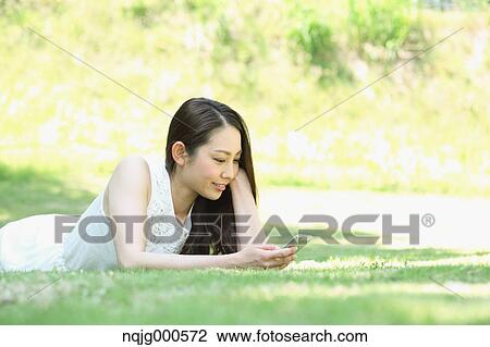 Portrait of young Japanese woman laying on grass with smartphone View Large Photo Image Stock Image - Portrait of young Japanese woman laying on grass with smartphone. Fotosearch