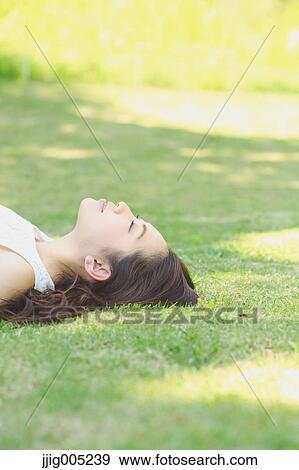Portrait of young Japanese woman laying on green grass View Large Photo Image Stock Photo - Portrait of young Japanese woman laying on green grass. Fotosearch