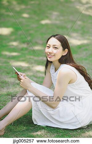 Portrait of young Japanese woman laying on grass with tablet View Large Photo Image Stock Photo - Portrait of young Japanese woman laying on grass with tablet. Fotosearch
