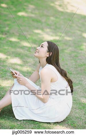 Portrait of young Japanese woman laying on grass with smartphone View Large Photo Image Stock Photo - Portrait of young Japanese woman laying on grass with smartphone. Fotosearch