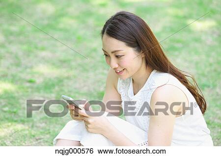 Portrait of young Japanese woman laying on grass with smartphone View Large Photo Image Stock Photograph - Portrait of young Japanese woman laying on grass with smartphone. Fotosearch