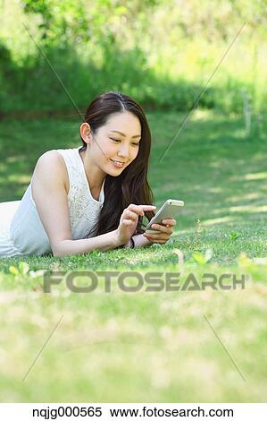 Portrait of young Japanese woman laying on grass with smartphone View Large Photo Image Stock Photography - Portrait of young Japanese woman laying on grass with smartphone. Fotosearch