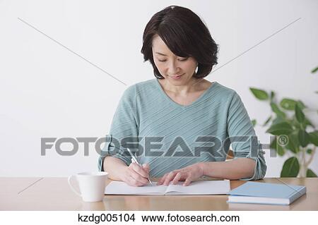 Picture - Senior Japanese woman doing accounting in the living room. Fotosearch