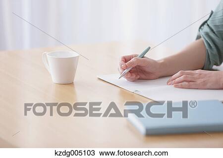 Stock Image - Senior Japanese woman doing accounting in the living room. Fotosearch