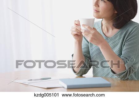 Stock Image - Senior Japanese woman having coffee in the living room. Fotosearch