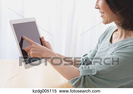 Stock Photography - Senior Japanese woman with tablet in the living room. Fotosearch