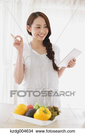 Young attractive Japanese woman cooking at home with tablet View Large Photo Image Picture - Young attractive Japanese woman cooking at home with tablet. Fotosearch