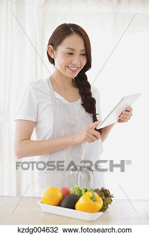 Young attractive Japanese woman cooking at home with tablet View Large Photo Image Stock Image - Young attractive Japanese woman cooking at home with tablet. Fotosearch