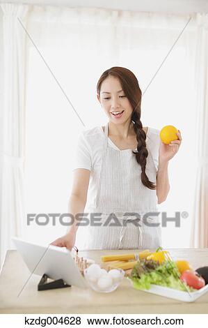 Young attractive Japanese woman cooking at home with tablet View Large Photo Image Stock Photo - Young attractive Japanese woman cooking at home with tablet. Fotosearch