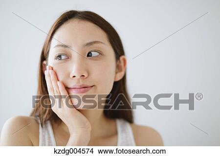 Picture - Young attractive Japanese woman doing skin care in the bathroom. Fotosearch