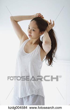 Young attractive Japanese woman doing her hair in the bathroom View Large Photo Image Picture - Young attractive Japanese woman doing her hair in the bathroom. Fotosearch