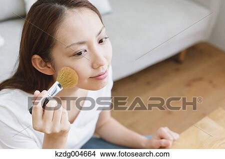 Picture - Young attractive Japanese woman doing her make-up at home. Fotosearch