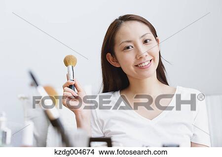 Picture - Young attractive Japanese woman doing her make-up at home. Fotosearch
