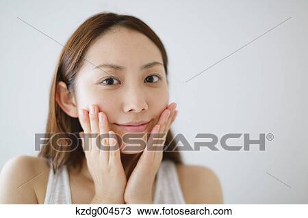 Stock Image - Young attractive Japanese woman doing skin care in the bathroom. Fotosearch