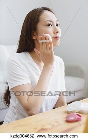 Stock Image - Young attractive Japanese woman doing her make-up at home. Fotosearch