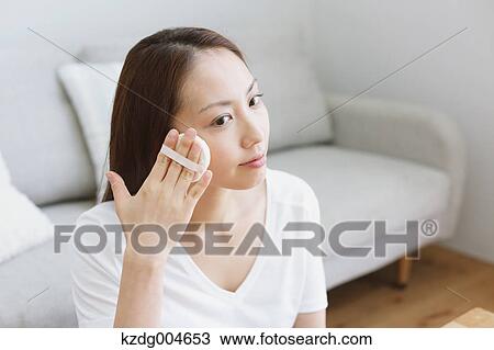 Stock Image - Young attractive Japanese woman doing her make-up at home. Fotosearch