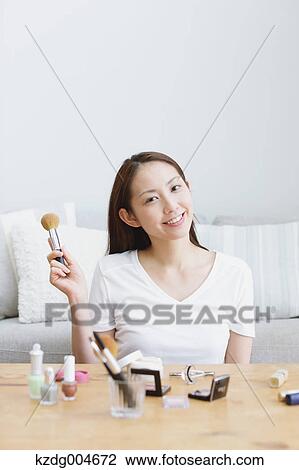 Stock Image - Young attractive Japanese woman doing her make-up at home. Fotosearch