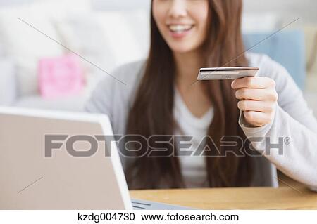 Stock Image - Young attractive Japanese woman doing online shopping at home. Fotosearch