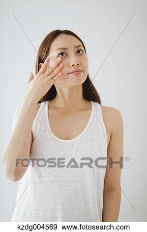 Stock Photo - Young attractive Japanese woman doing skin care in the bathroom. Fotosearch