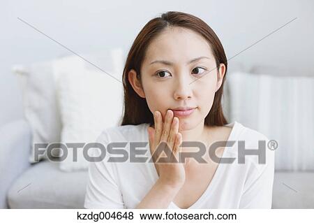 Stock Photo - Young attractive Japanese woman doing her make-up at home. Fotosearch