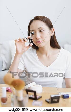 Stock Photo - Young attractive Japanese woman doing her make-up at home. Fotosearch