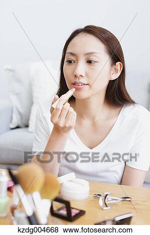 Stock Photo - Young attractive Japanese woman doing her make-up at home. Fotosearch