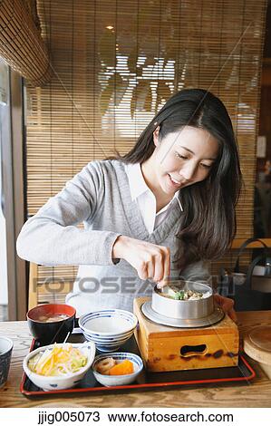 Stock Image - Young attractive Japanese woman eating at the restaurant. Fotosearch